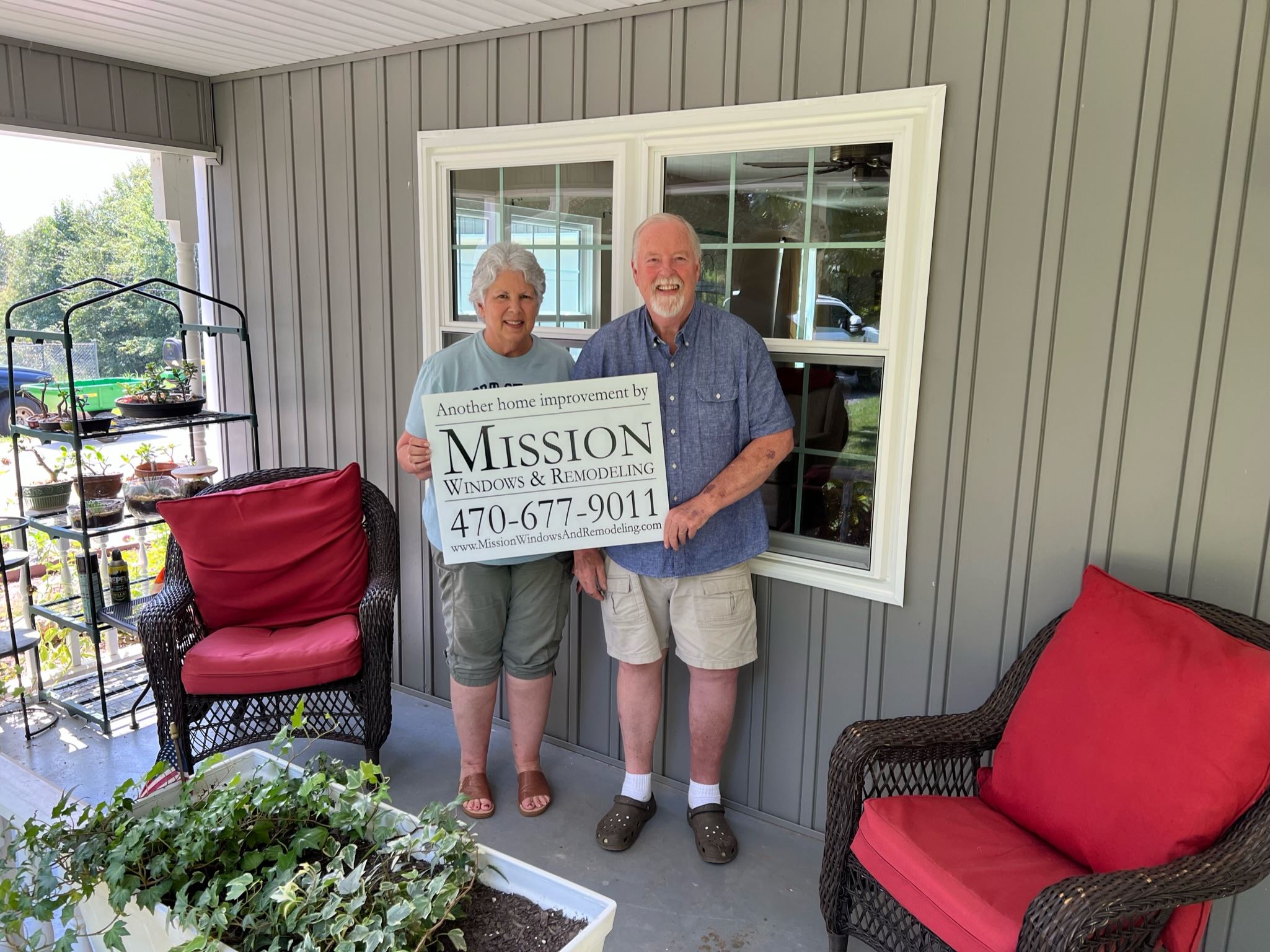 A couple holding a Mission Windows and Remodeling sign